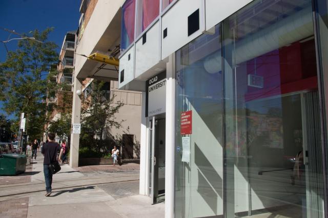 Photo of the “OCAD University” sign at 51 McCaul as seen from the sidewalk on the same side of the street as the building